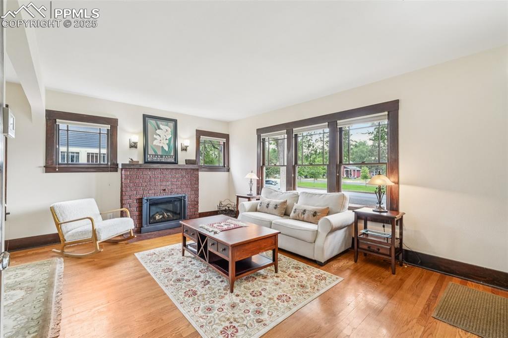 Image 11 of 49: Living room featuring a brick fireplace and light wood-style floors