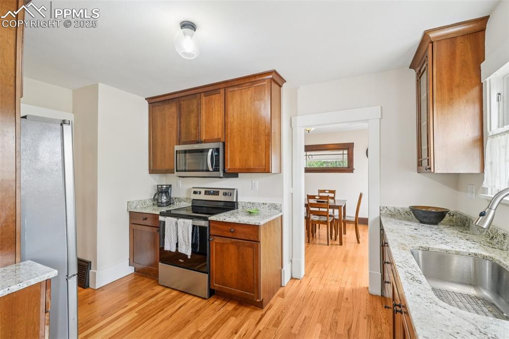 Image 17 of 49: Kitchen with stainless steel appliances, light wood-type flooring, brown ca