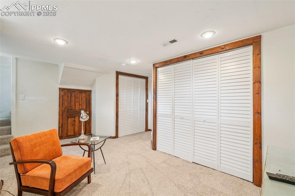 Image 33 of 49: Downstairs sitting room with light colored carpet and recessed lighting
