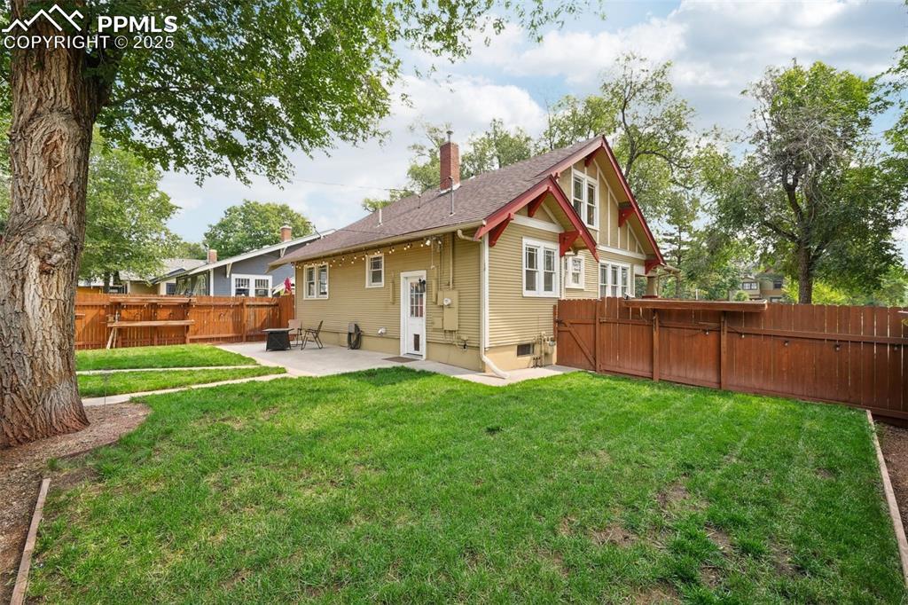 Image 42 of 49: Back of house featuring a patio area, a chimney, a fenced backyard, and a g