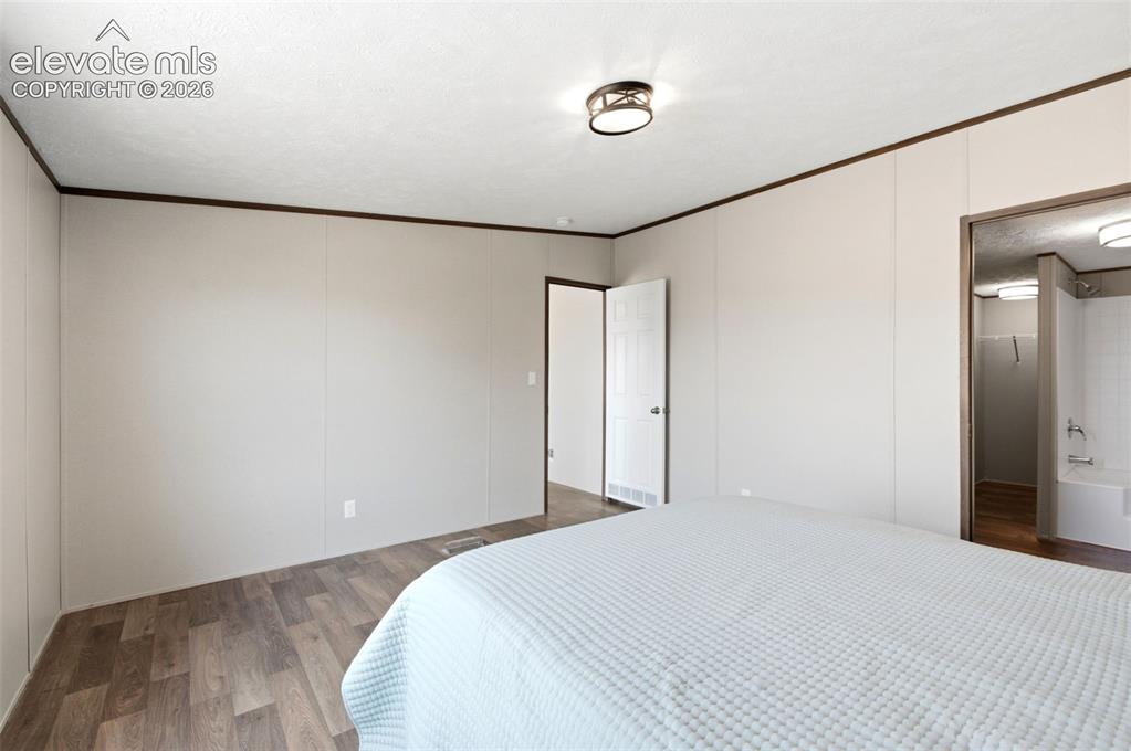 Image 11 of 32: Spacious room featuring wood-finish flooring, light-toned walls, and a cont