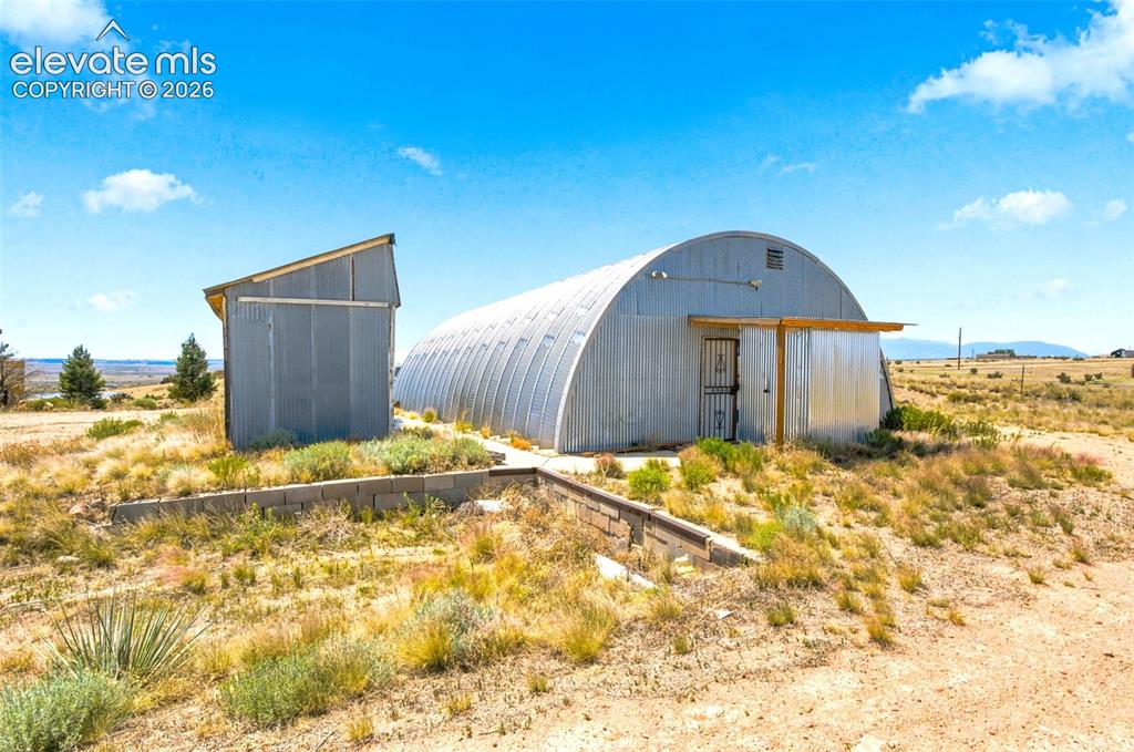 Image 20 of 32: Quonset hut structure featuring corrugated metal siding and an attached lea