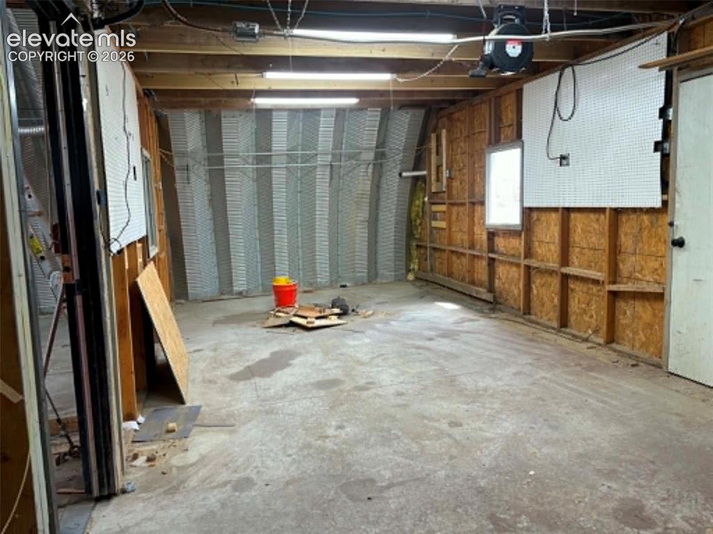 Image 24 of 32: Spacious workshop area featuring exposed ceiling joists, concrete flooring,