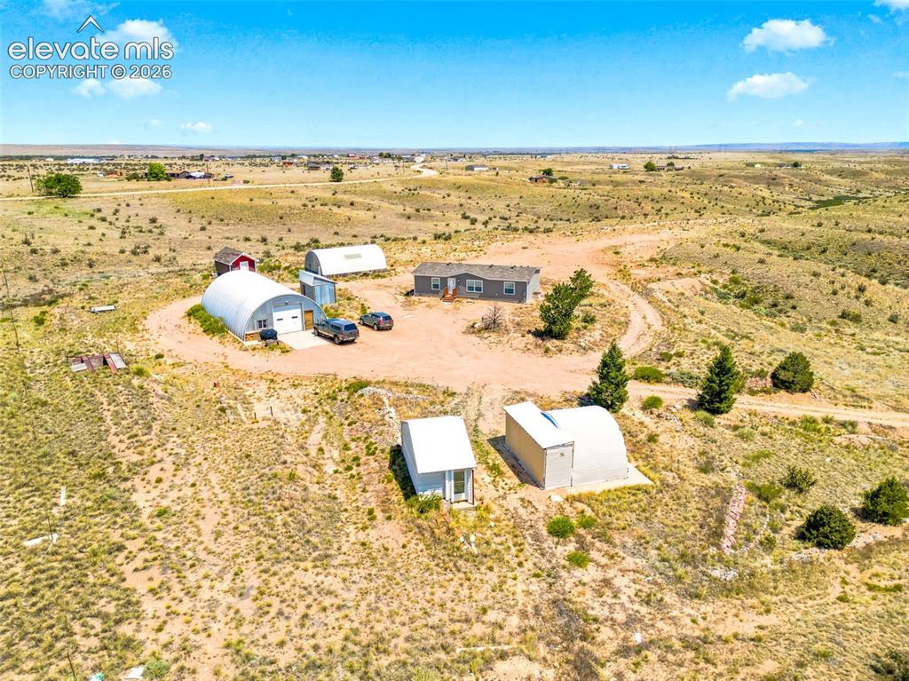 Image 28 of 32: Expansive property featuring a central residence, multiple metal outbuildin