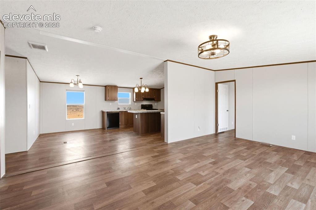 Image 3 of 32: Expansive open-concept living area featuring wood-finish flooring, white pa