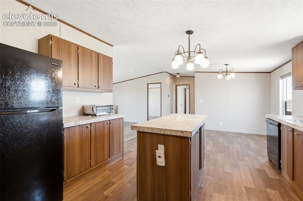 Image 8 of 32: Kitchen featuring wood-finish flooring, an island with countertop, wood-ton