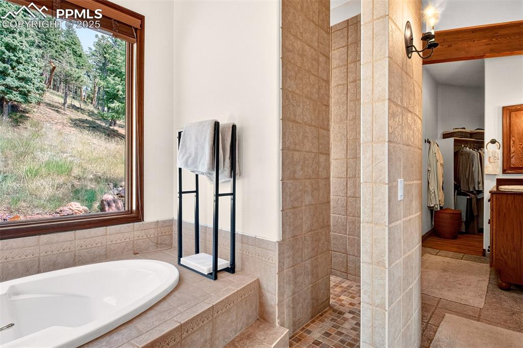 Image 18 of 50: Primary en suite bathroom with soaking tub, custom shower and walk in close