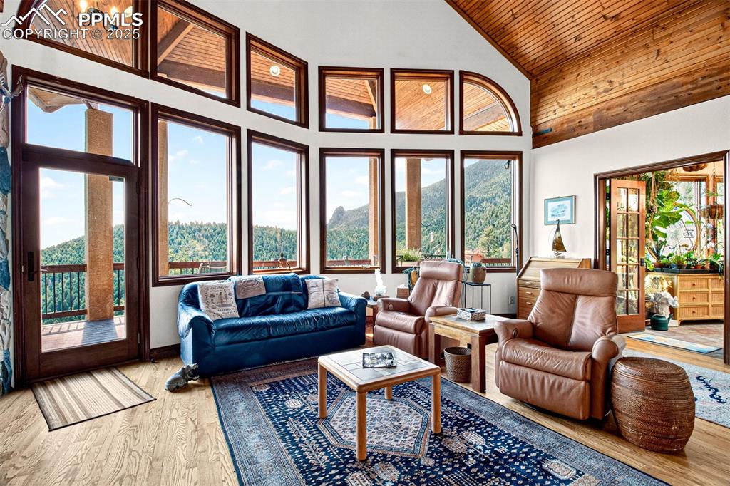 Image 9 of 50: Living room on main level with wood flooring, vaulted ceilings and windows 