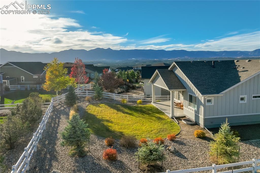 Image 36 of 50: Covered concrete patio surrounded by professional landscaping + mountain vi