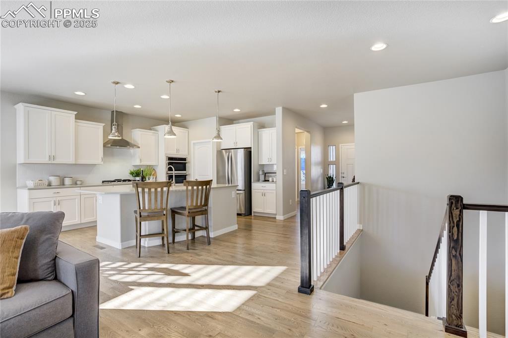 Image 8 of 50: A true centerpiece—grand island, quartz countertops, pendant lighting, and 