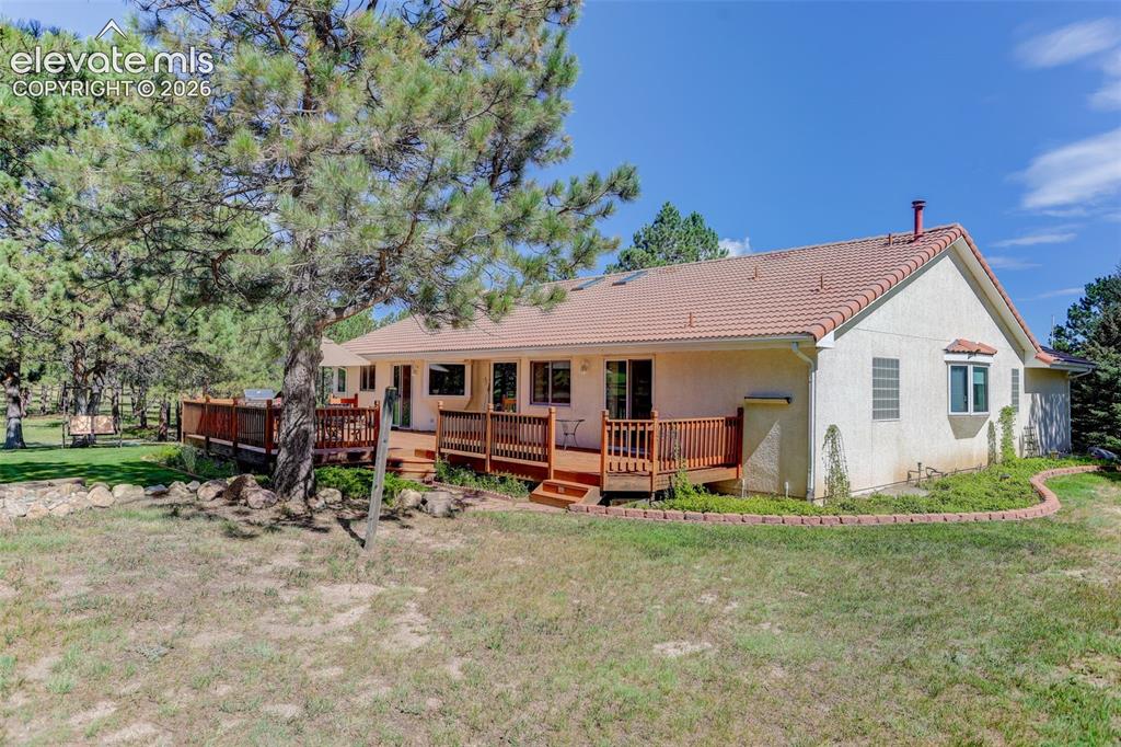 Image 2 of 49: Back and side of structure. Back deck and garden along home. 