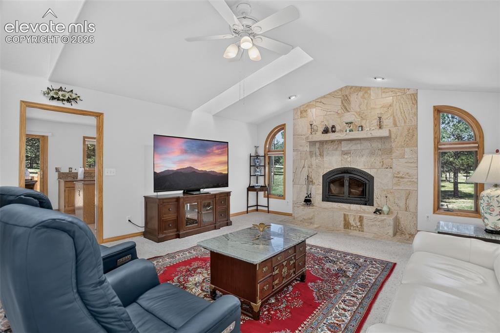 Image 21 of 49: Family room with wood fireplace, skylights, and ceiling fan.