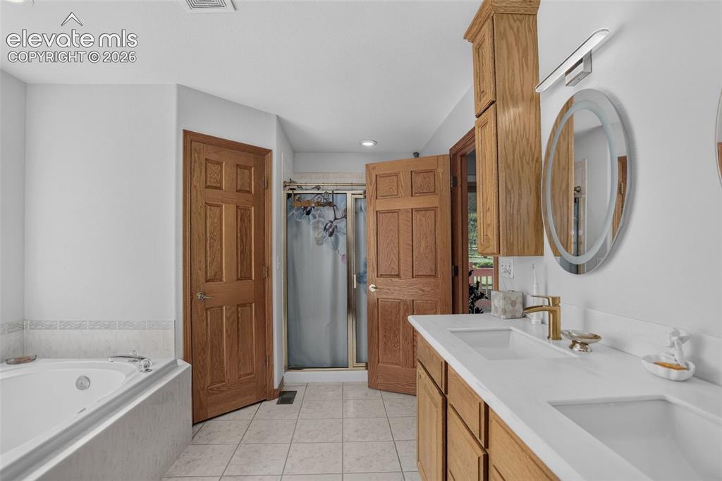 Image 27 of 49: Primary bathroom with jetted tub, double vanity, and free standing shower. 