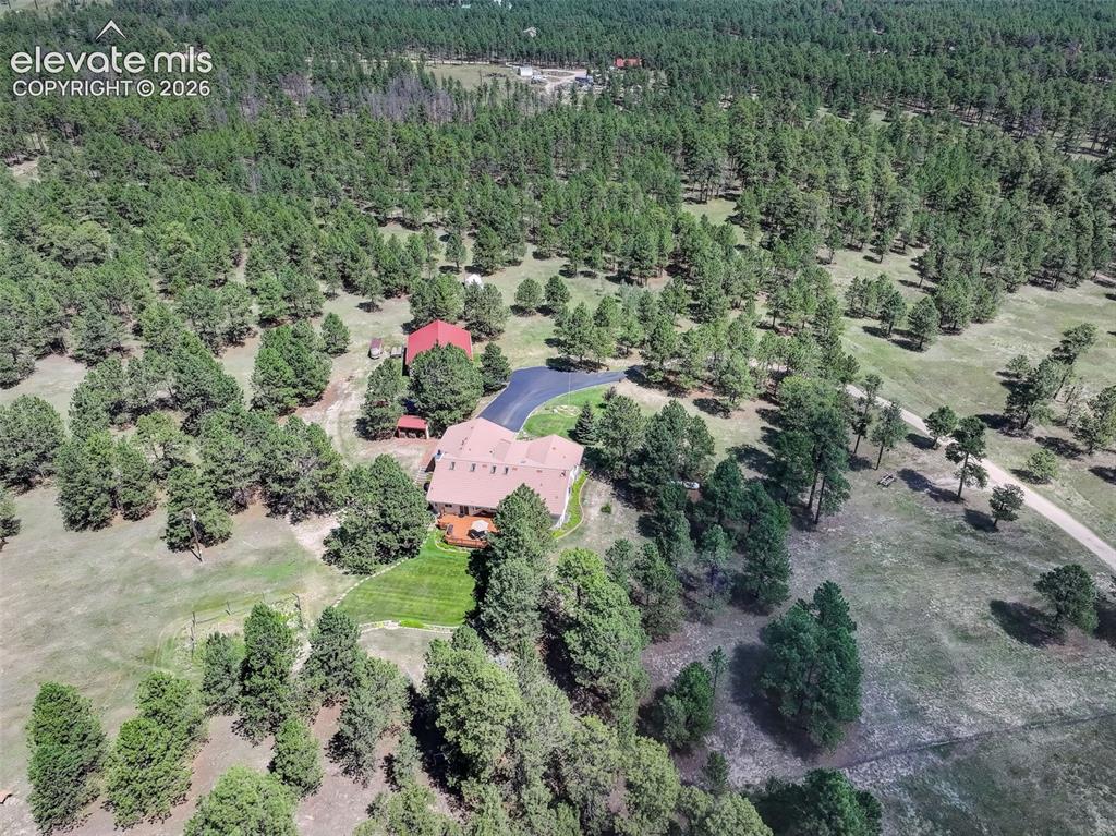 Image 49 of 49: Aerial view highlighting landscaped areas of property and sheds. 