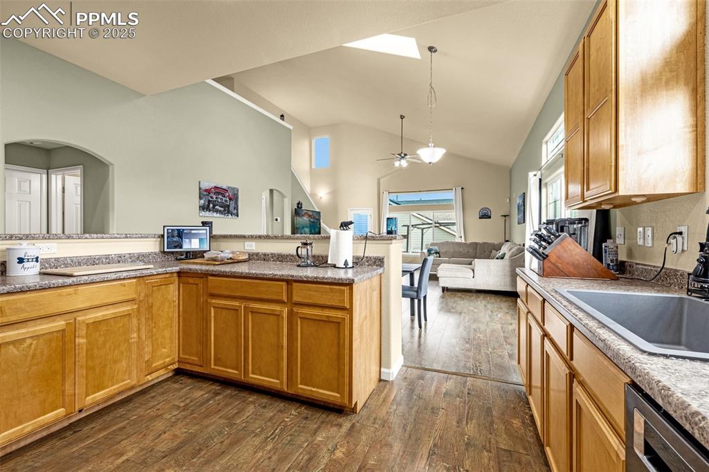 Image 11 of 36: Kitchen with open floor plan, brown cabinets, dark wood-style floors, ceili