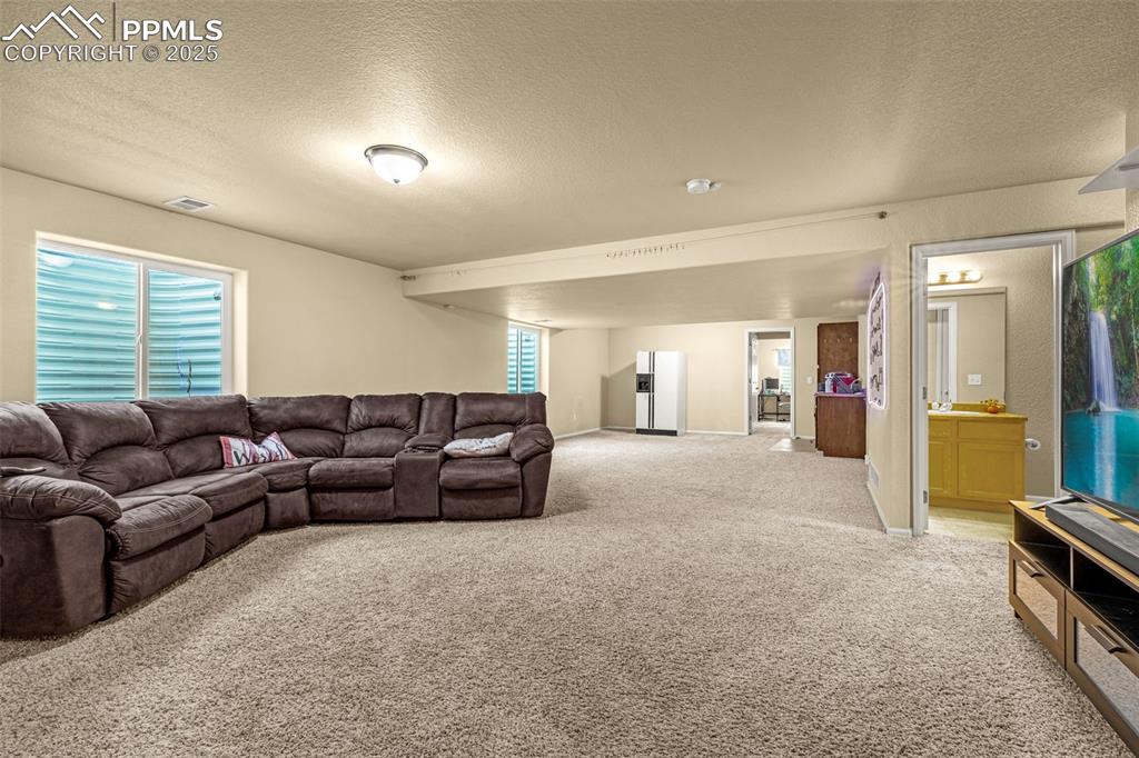 Image 21 of 36: Living room with a textured ceiling and light colored carpet