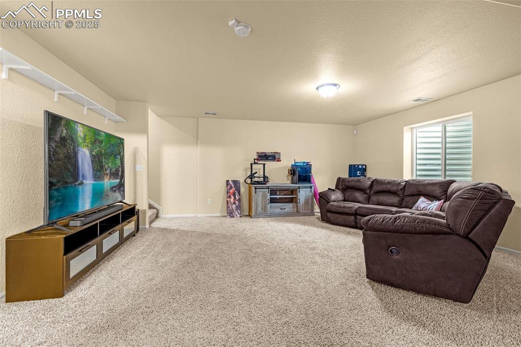 Image 22 of 36: Living area with carpet floors and a textured ceiling