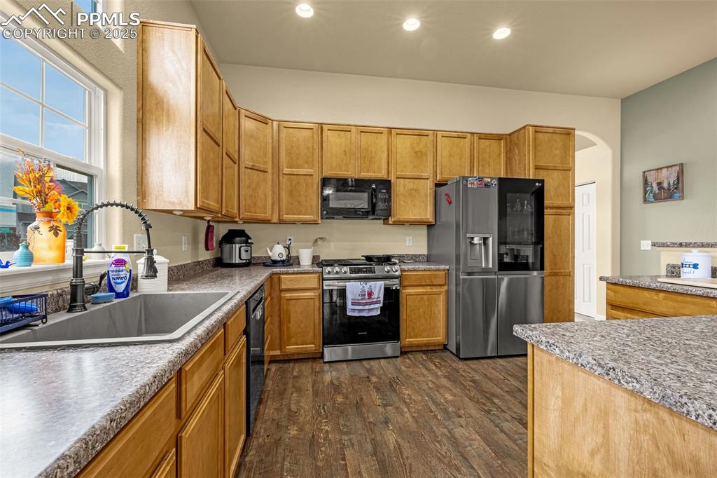 Image 4 of 36: Kitchen featuring black appliances, dark wood-style floors, brown cabinets,
