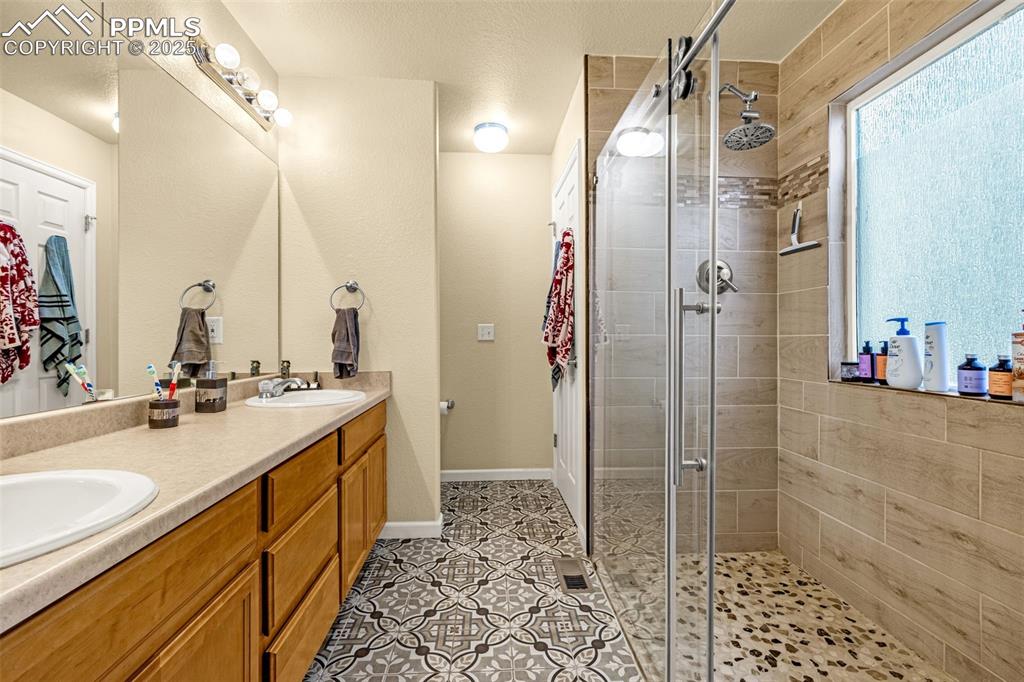 Image 5 of 36: Full bath featuring double vanity, a stall shower, light tile patterned flo