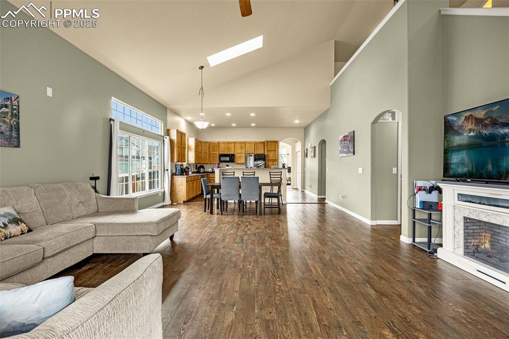 Image 9 of 36: Living area with high vaulted ceiling, a skylight, dark wood-type flooring,