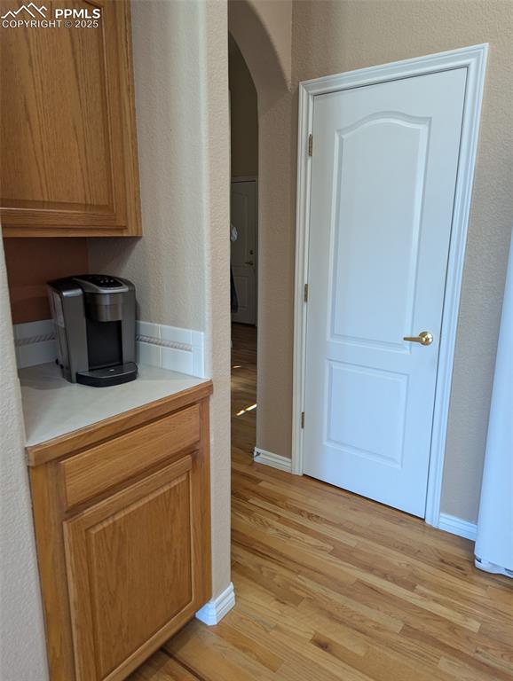 Image 12 of 33: Kitchen featuring a textured wall, light countertops, light wood-type floor
