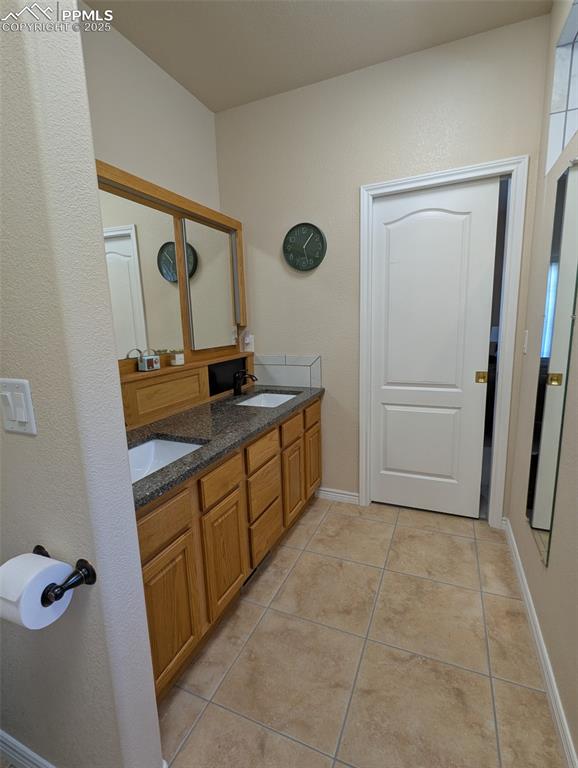Image 18 of 33: Bathroom featuring double vanity, light tile patterned flooring, and a text