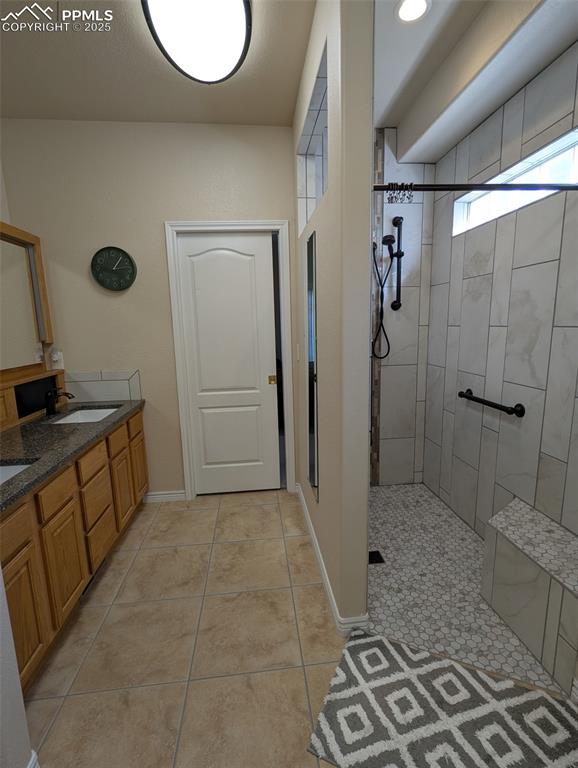 Image 19 of 33: Full bathroom with double vanity, a walk in shower, and light tile patterne