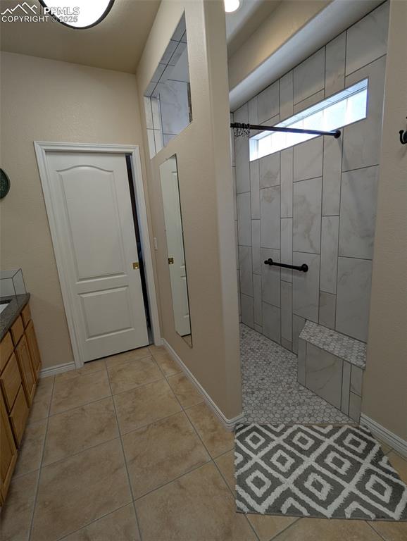 Image 20 of 33: Full bath with walk in shower, light tile patterned flooring, and vanity