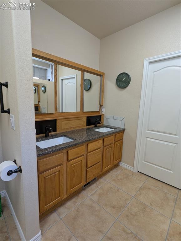 Image 21 of 33: Full bathroom with light tile patterned flooring, double vanity, and a text