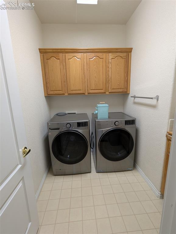 Image 22 of 33: Laundry room with washer and clothes dryer, light tile patterned flooring,