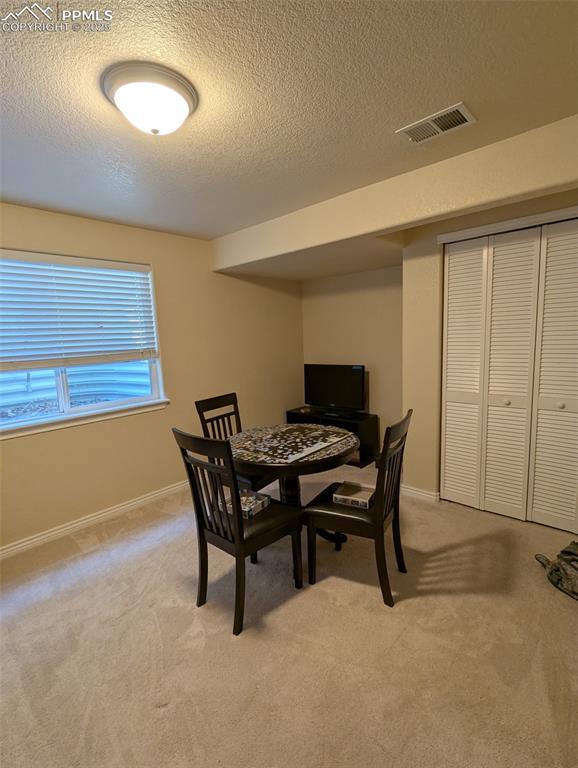 Image 26 of 33: Dining space with a textured ceiling and light carpet