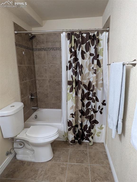Image 28 of 33: Full bath with a textured wall, light tile patterned flooring, and shower /