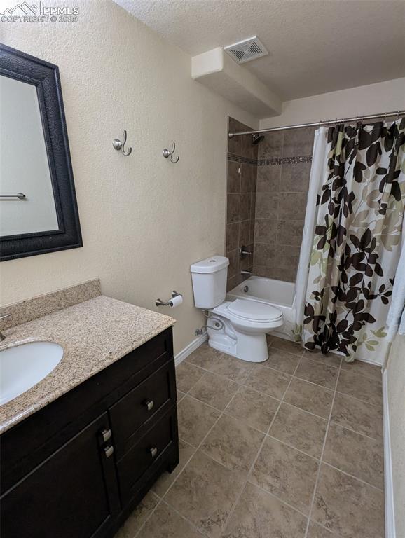Image 29 of 33: Bathroom with vanity, a textured wall, a textured ceiling, light tile patte