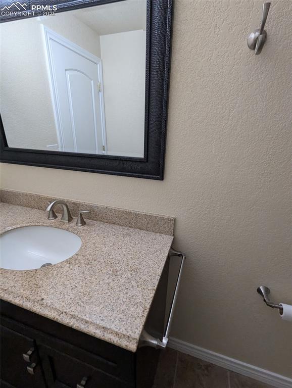 Image 30 of 33: Bathroom featuring a textured wall, vanity, and tile patterned floors