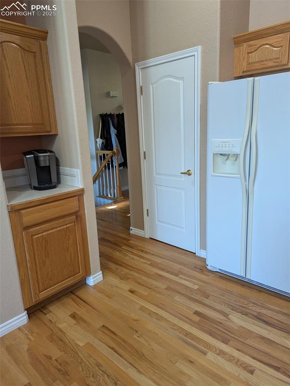 Image 7 of 33: Kitchen with white refrigerator with ice dispenser, arched walkways, light