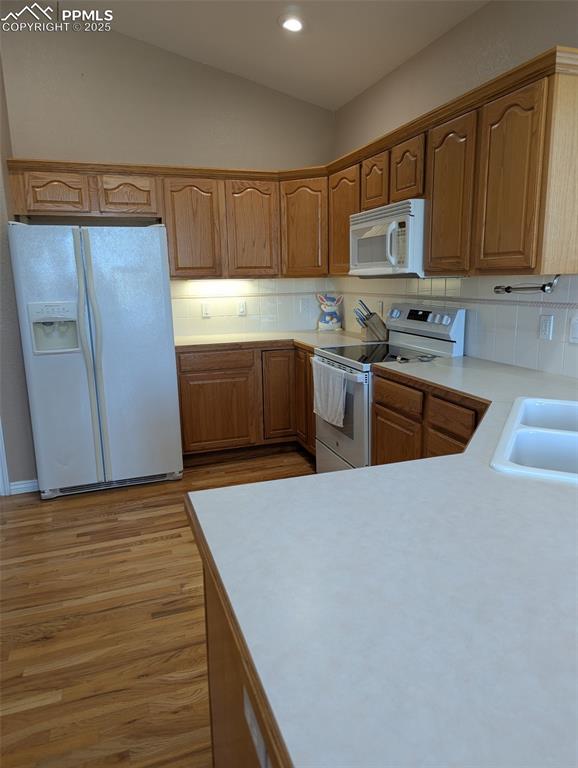 Image 9 of 33: Kitchen with light countertops, tasteful backsplash, white appliances, brow