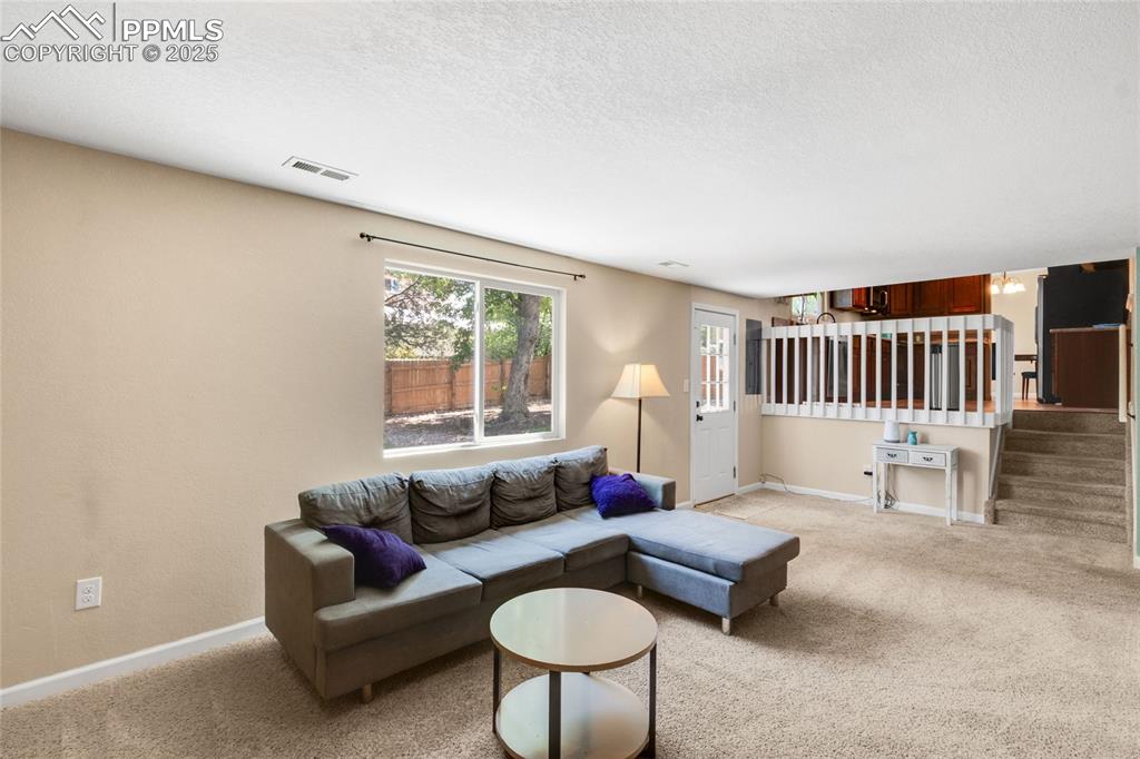 Image 8 of 43: Living room featuring light colored carpet, baseboards, a textured ceiling,