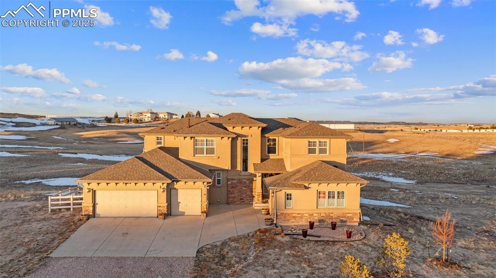 Caption: Front of  home featuring stone siding, stucco siding, driveway, a garage, and roof with shingles