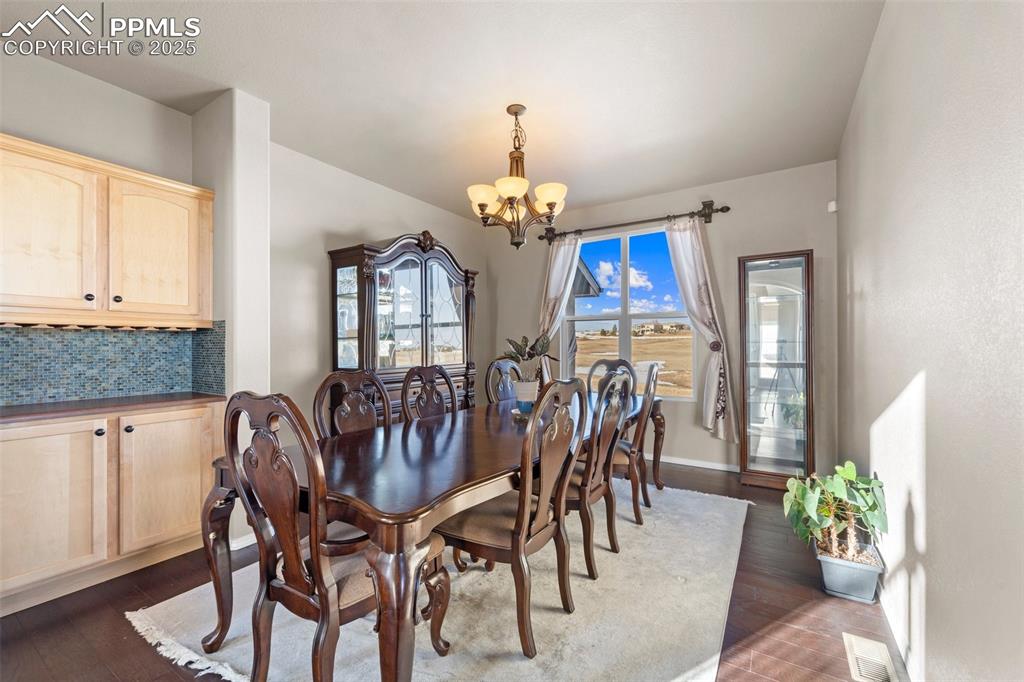 Image 14 of 50: Dining area featuring an inviting chandelier and dark hardwood / wood-style