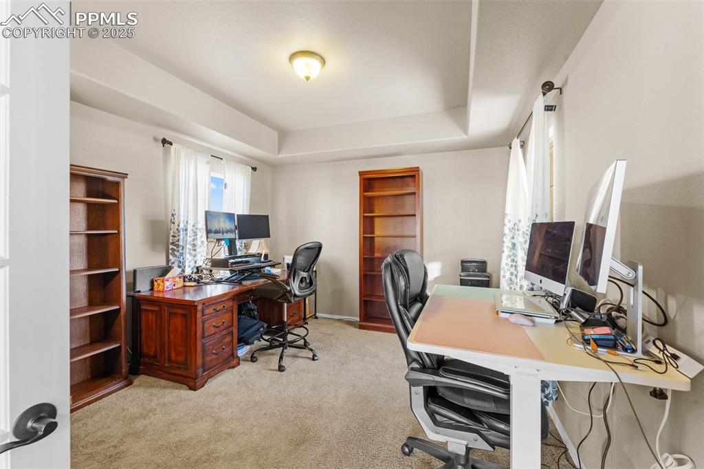 Image 17 of 50: Office area featuring light carpet and a tray ceiling