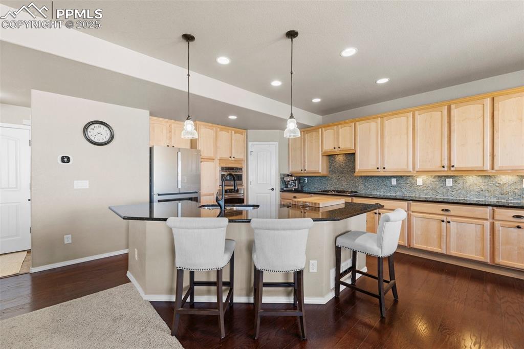 Image 21 of 50: Kitchen with pendant lighting, light brown cabinetry, refrigerator, and a c