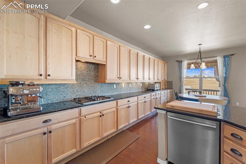 Image 23 of 50: Kitchen with stainless steel appliances, decorative light fixtures, dark ha
