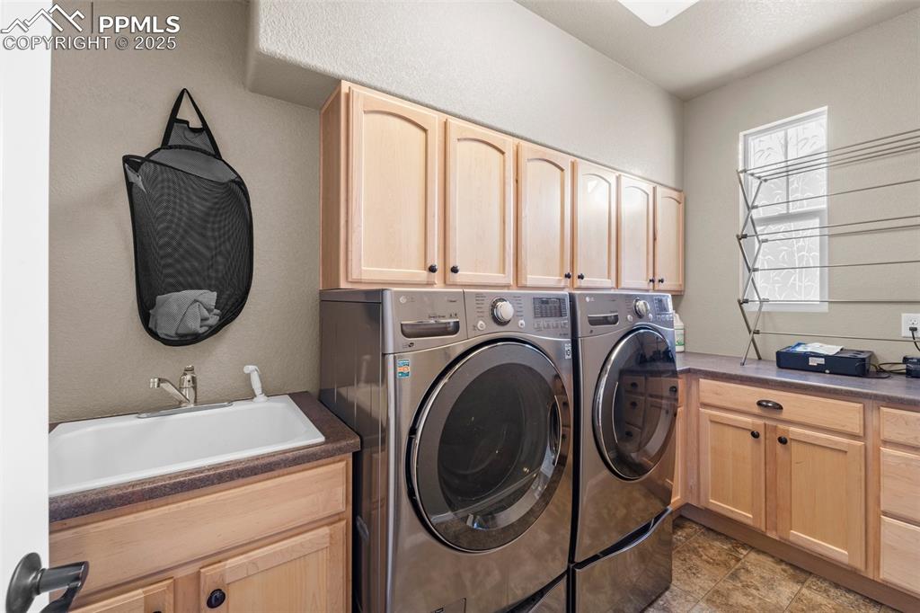 Image 26 of 50: Washroom featuring cabinets, separate washer and dryer, and sink