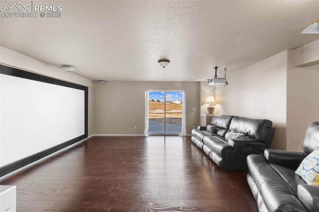 Image 27 of 50: Cinema featuring dark hardwood / wood-style flooring and a textured ceiling