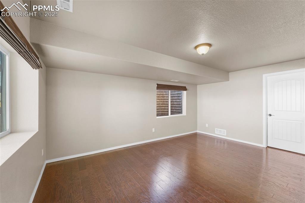 Image 28 of 50: Unfurnished room featuring wood-type flooring and a textured ceiling