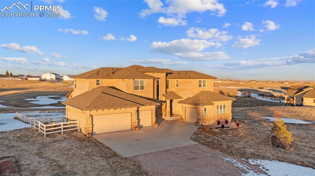 Image 3 of 50: Front of home with a shingled roof, driveway, stone siding, and stucco sidi