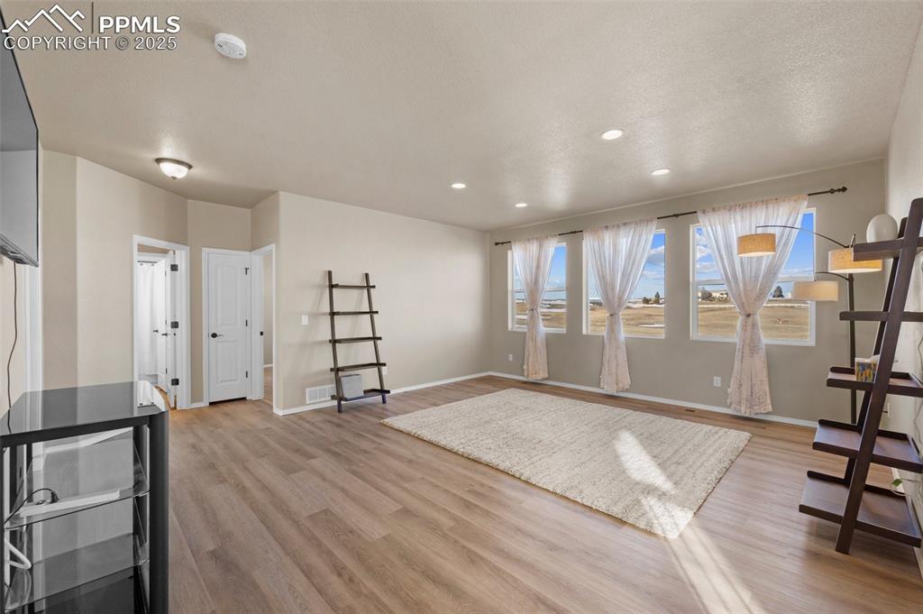 Image 34 of 50: Workout room featuring light hardwood / wood-style flooring and a textured
