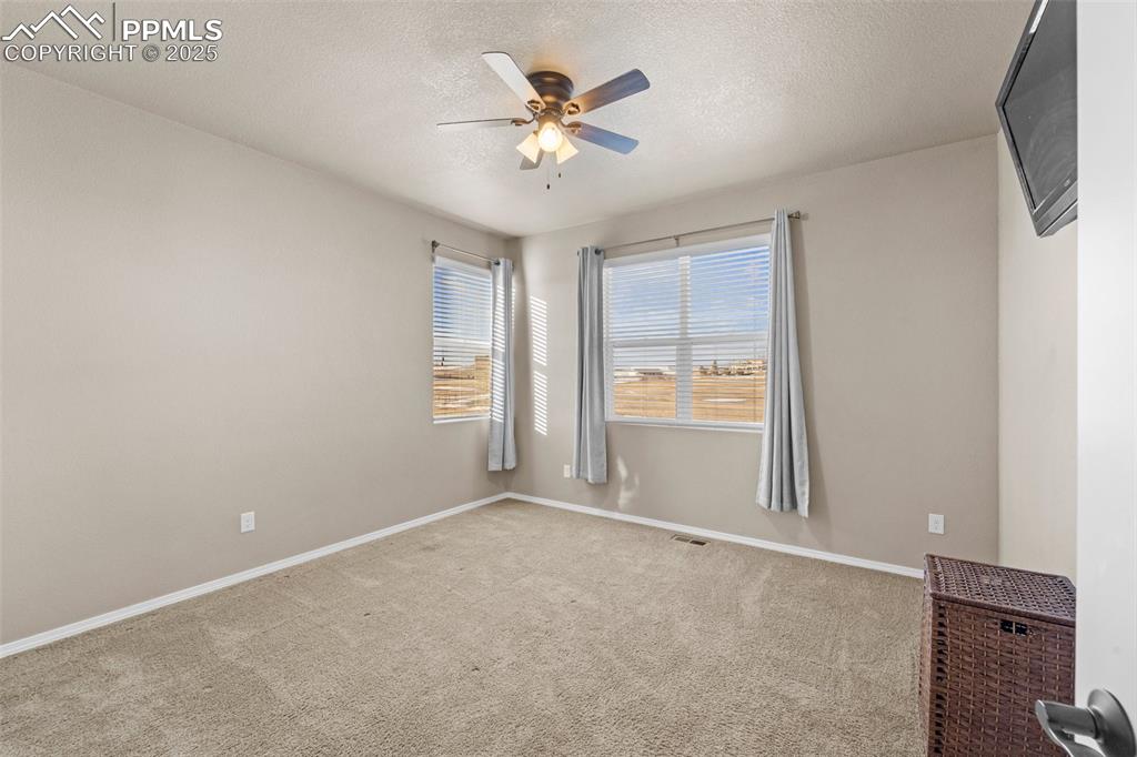 Image 36 of 50: Unfurnished room with a textured ceiling, ceiling fan, and carpet