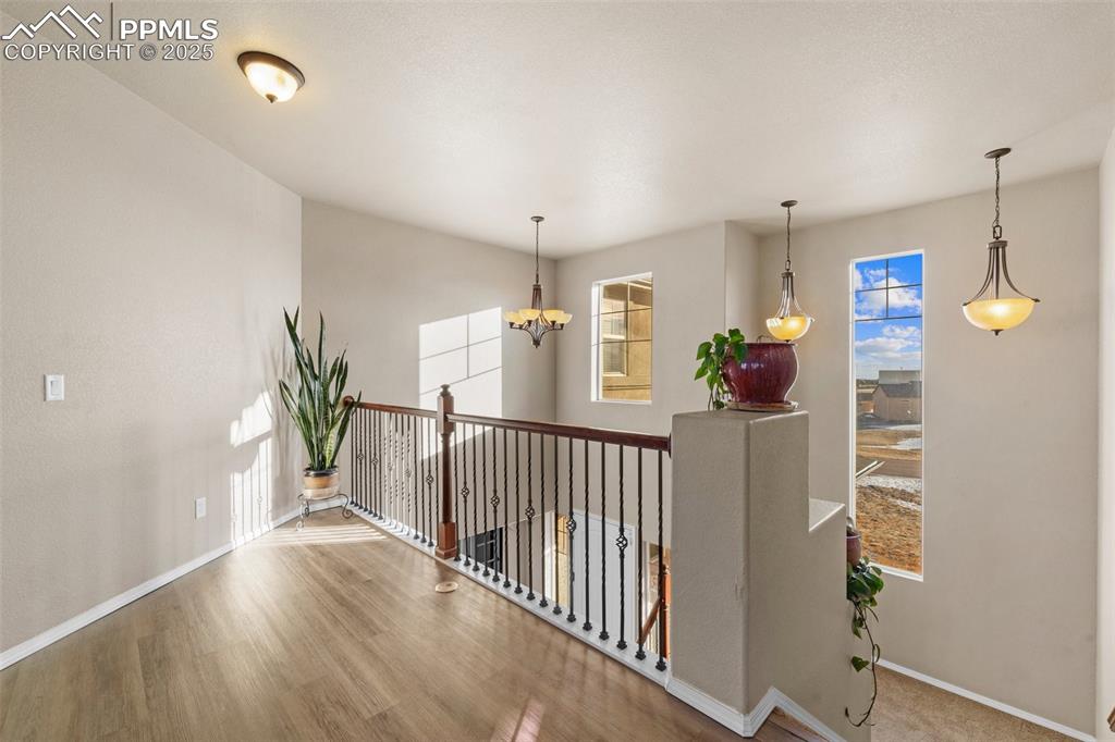 Image 39 of 50: Hallway featuring hardwood / wood-style flooring and a notable chandelier