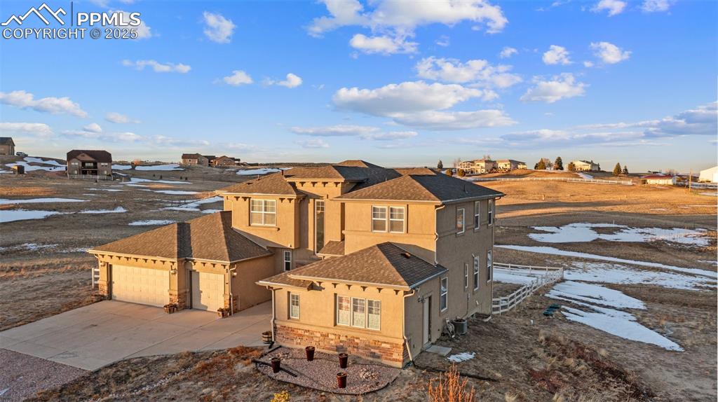 Image 4 of 50: View of front facade featuring stucco siding, driveway, roof with shingles,